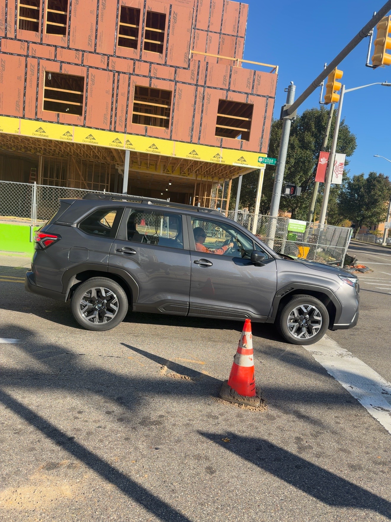 A vehicle at an intersection in front of a building under construction.